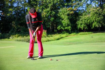 person wearing a black shirt and red pants playing golf