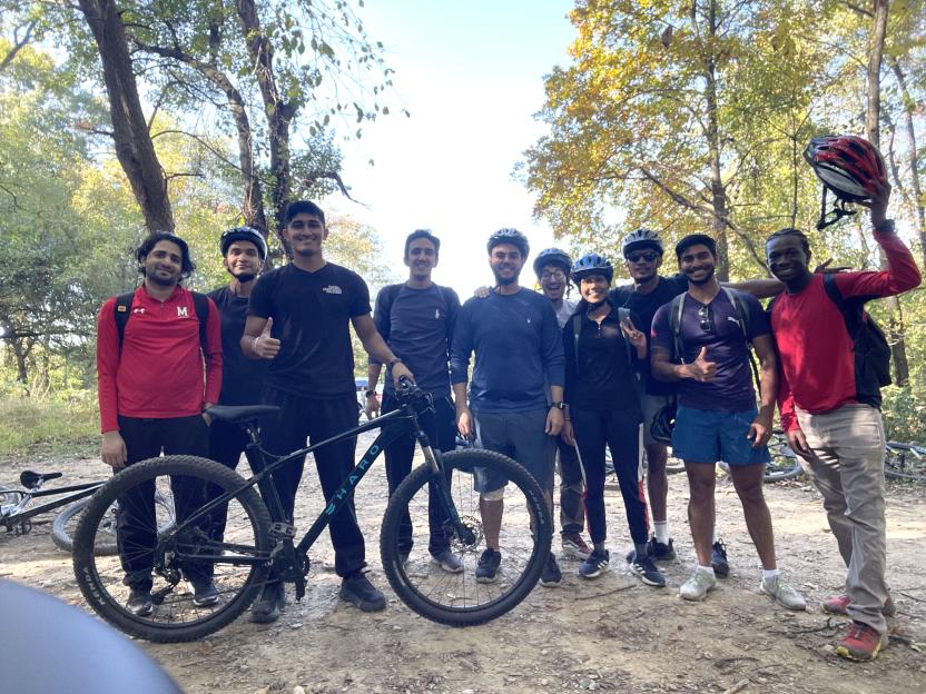 Students posing with a bike in the forest on an adventure trip