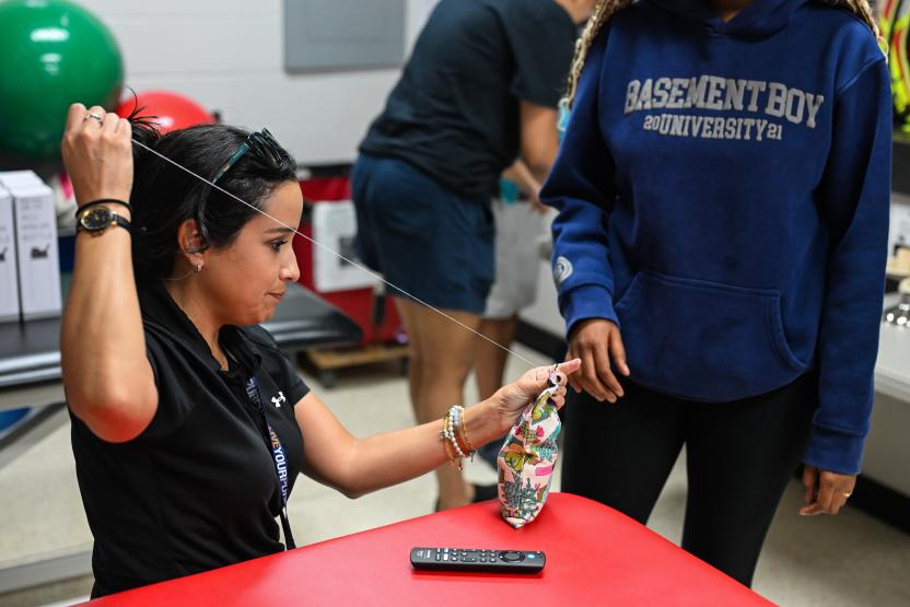 An athletic trainer helps a student sew their hot pack closed during a DIY event.