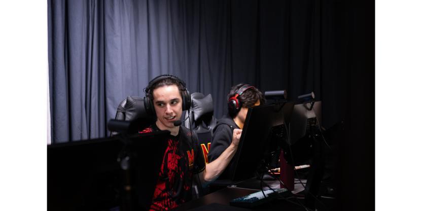 Terps Esports player fistbumping his teammates while they sit at their computers. 