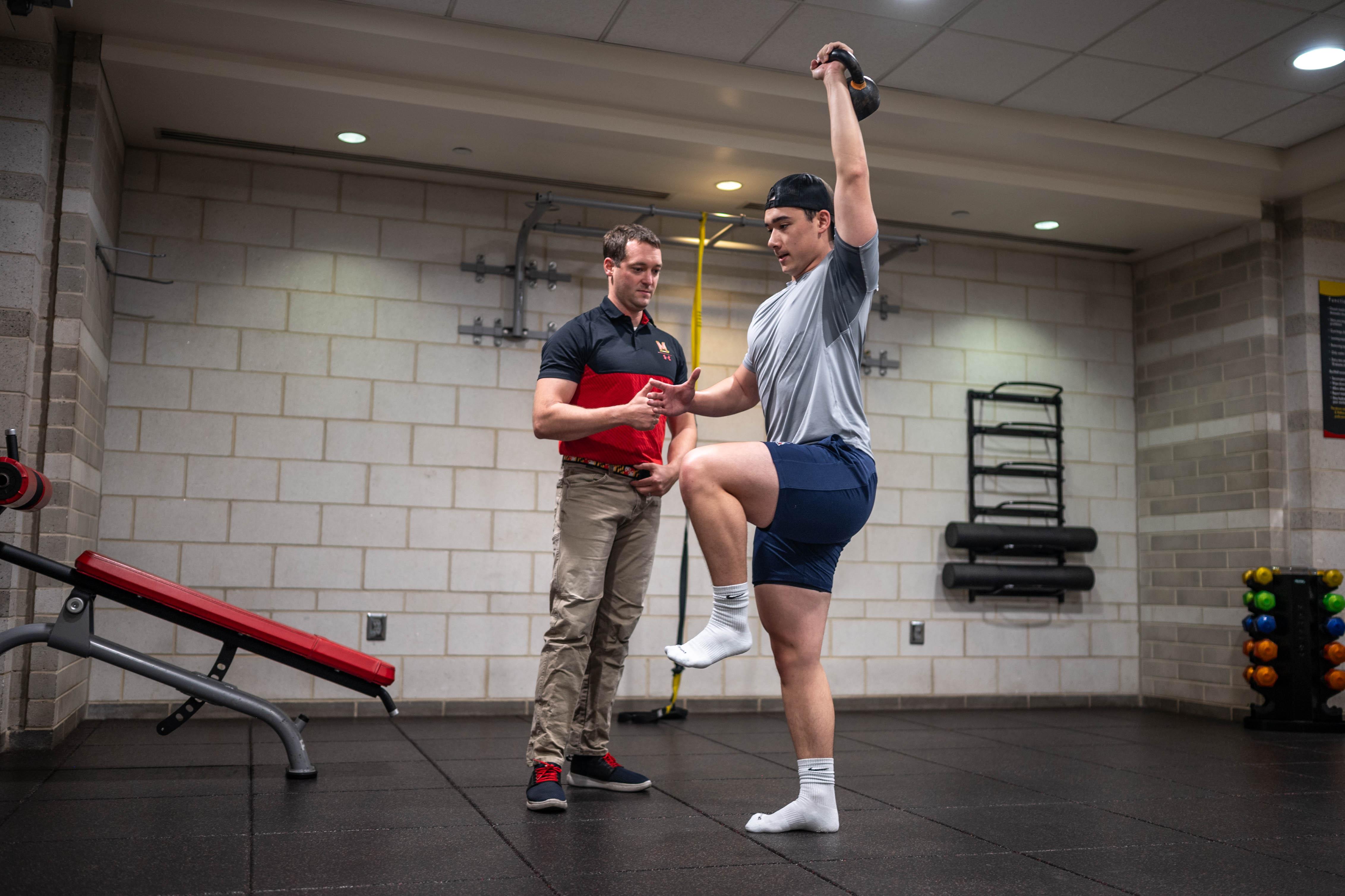 trainer watches athlete using kettlebell
