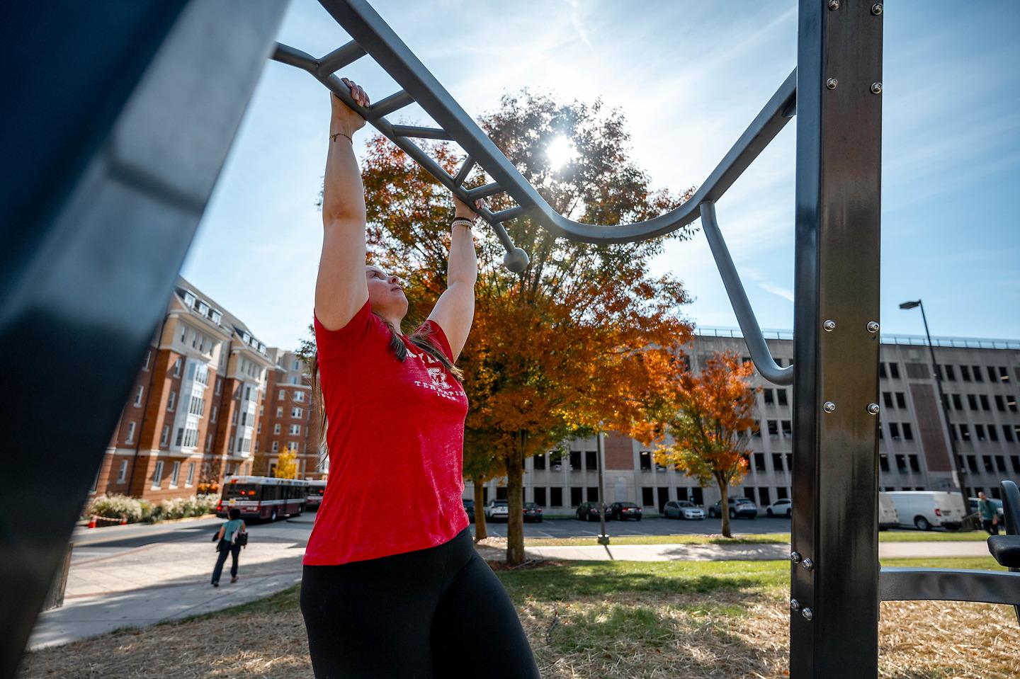 woman doing monkey bars on outdoor course