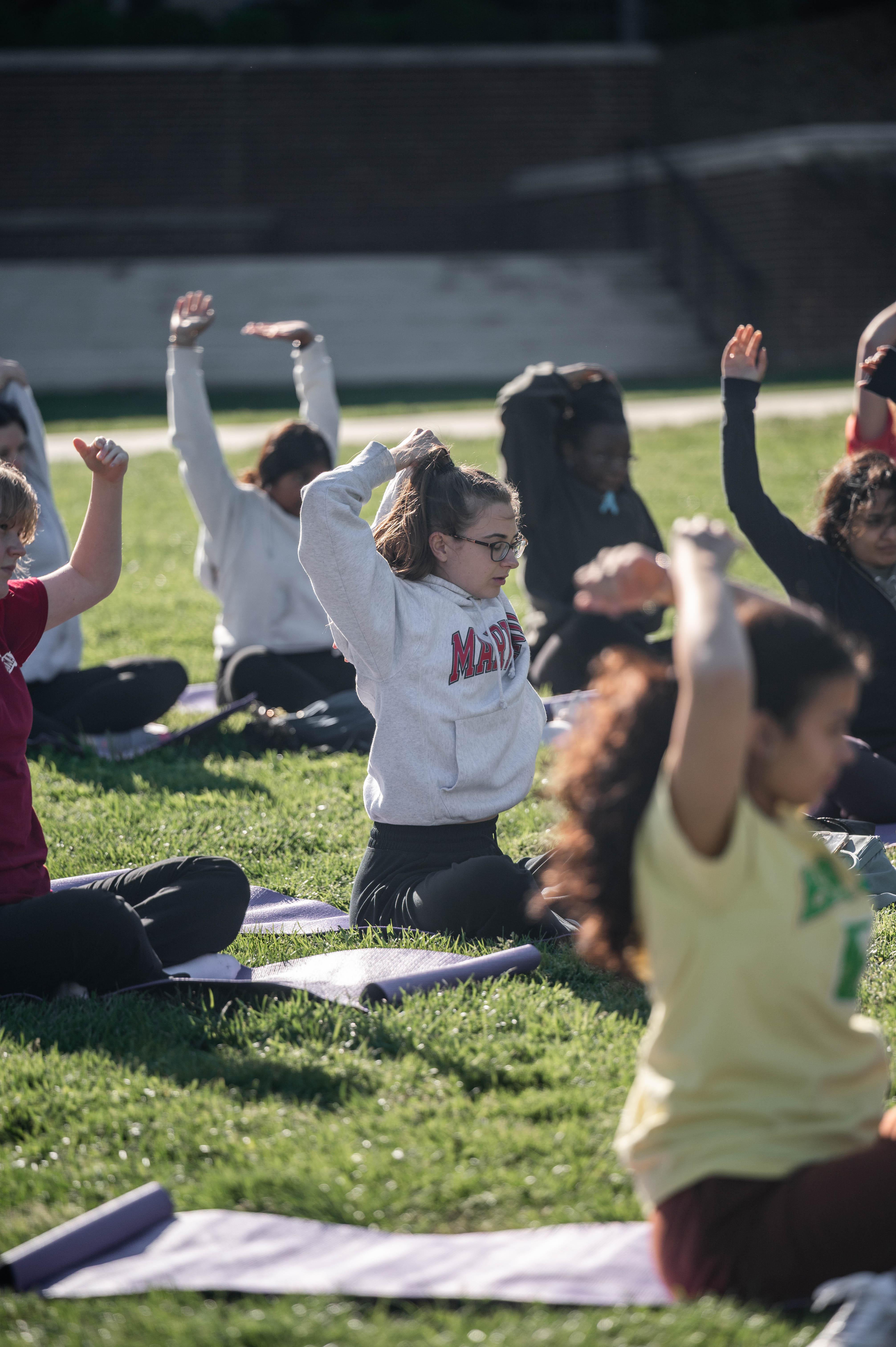 Group of people stretching outside while sitting