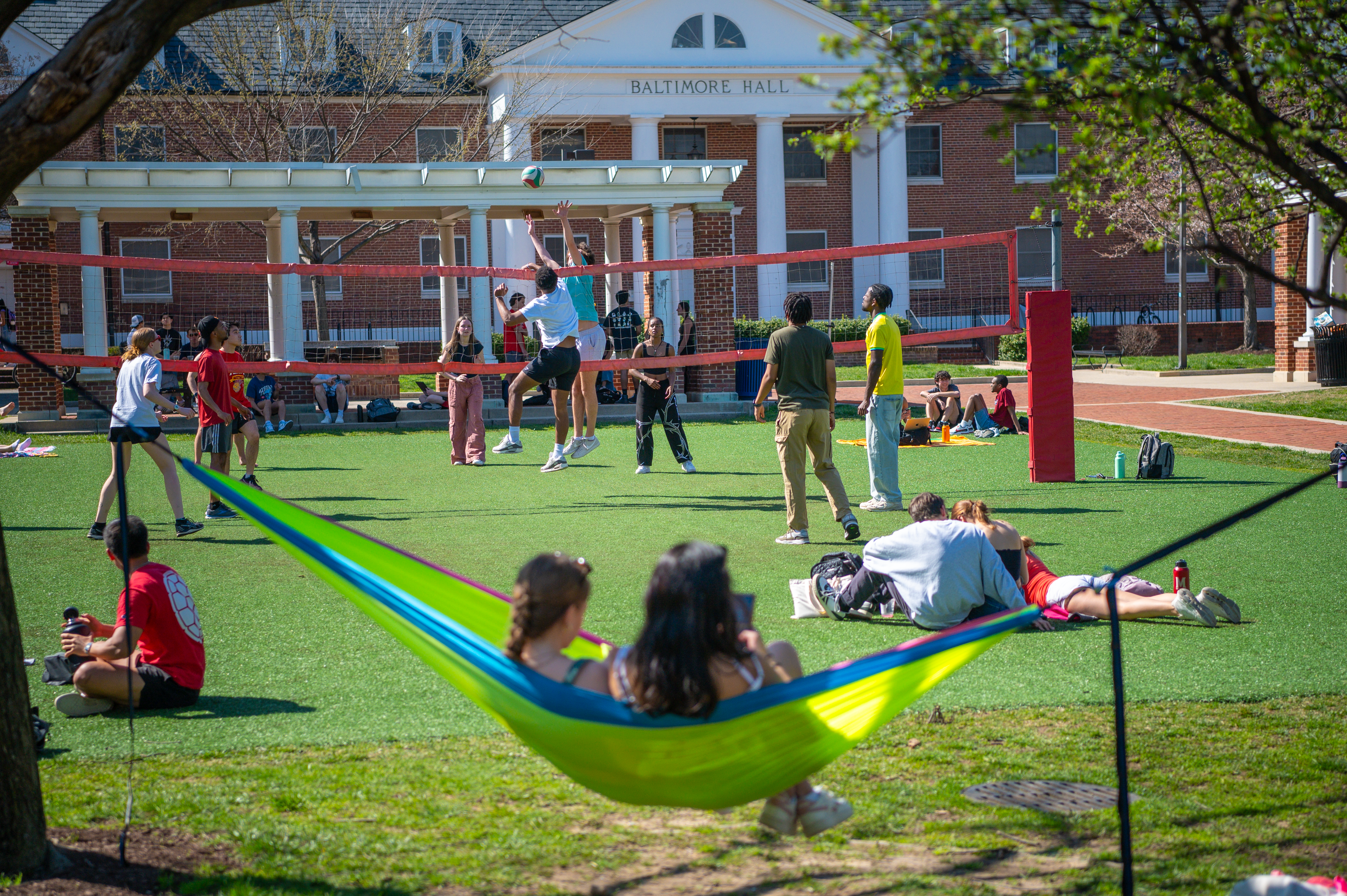 students lounging outside and playing volleyball