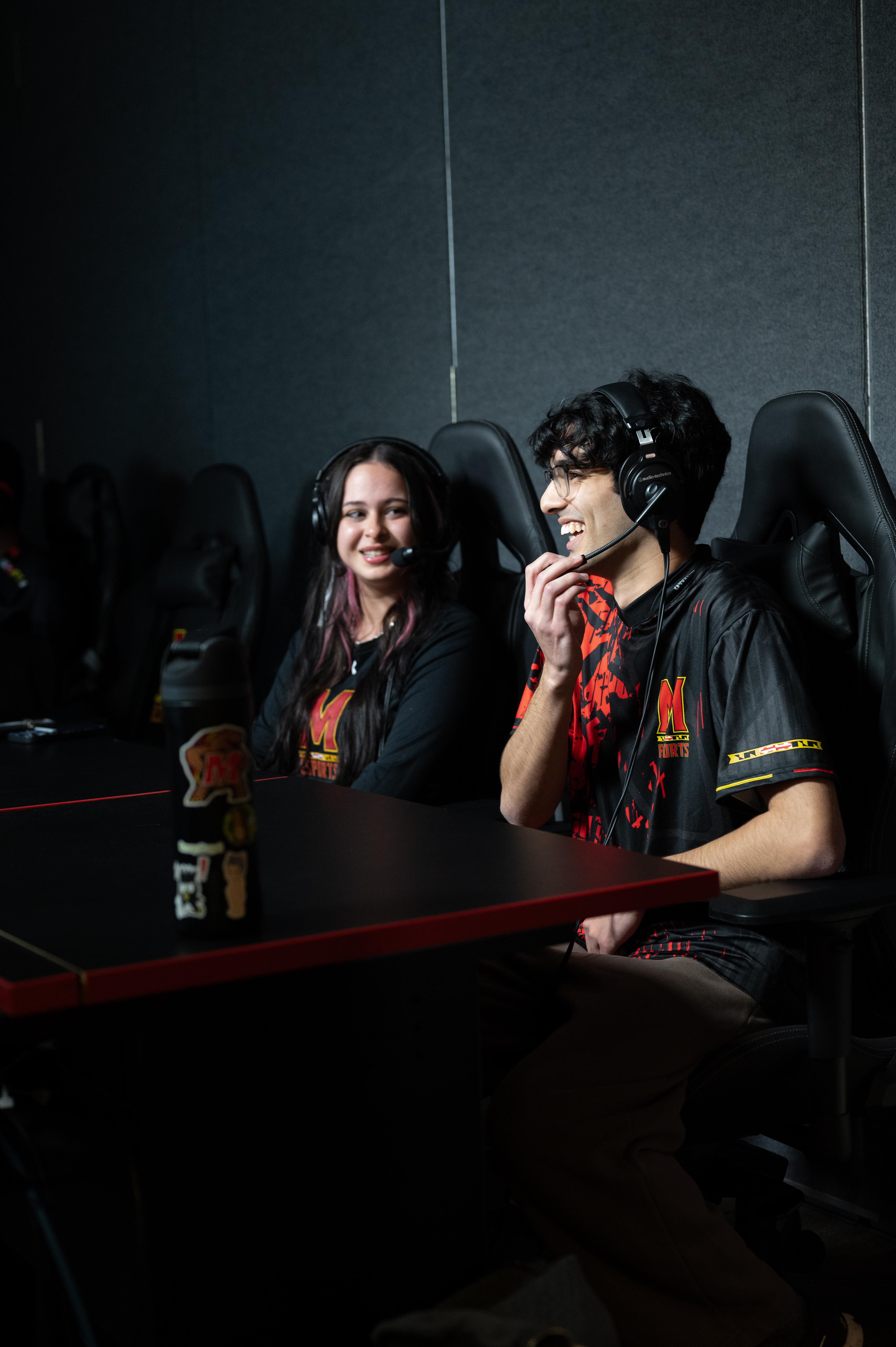 A Terps Esports broadcaster and player chat in front of the camera, with headsets on.